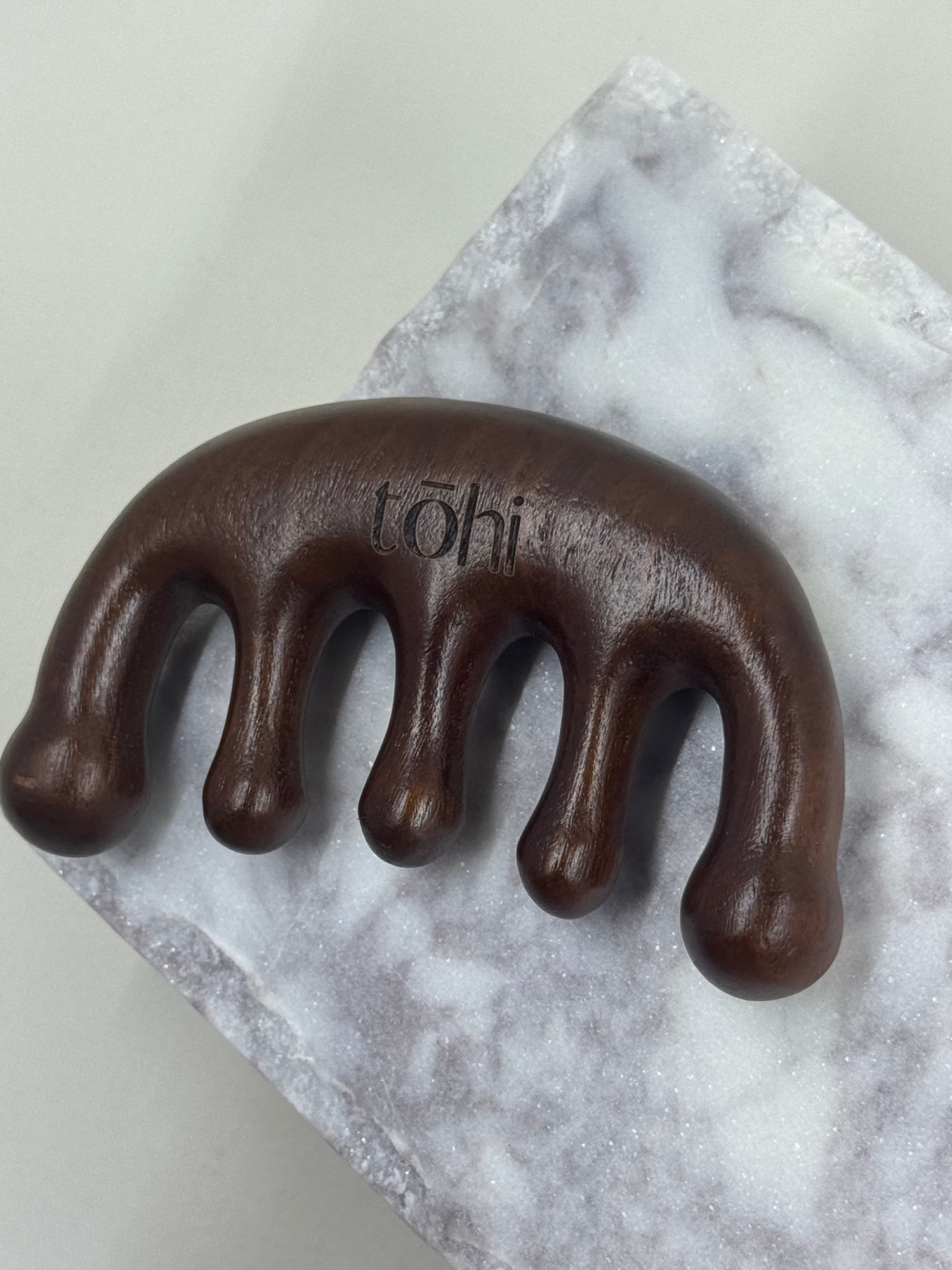 Brown handheld massager on a marble surface